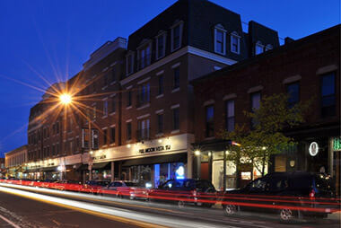 Exterior view of South and Hickory Place at night with cars passing by.