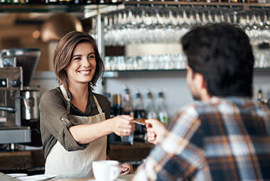 Barista hands credit card back to man at coffee sop