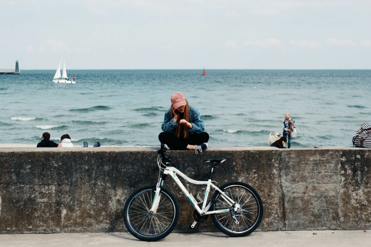 Woman sitting on pier with bicycle. Photo credit: Pawel L.