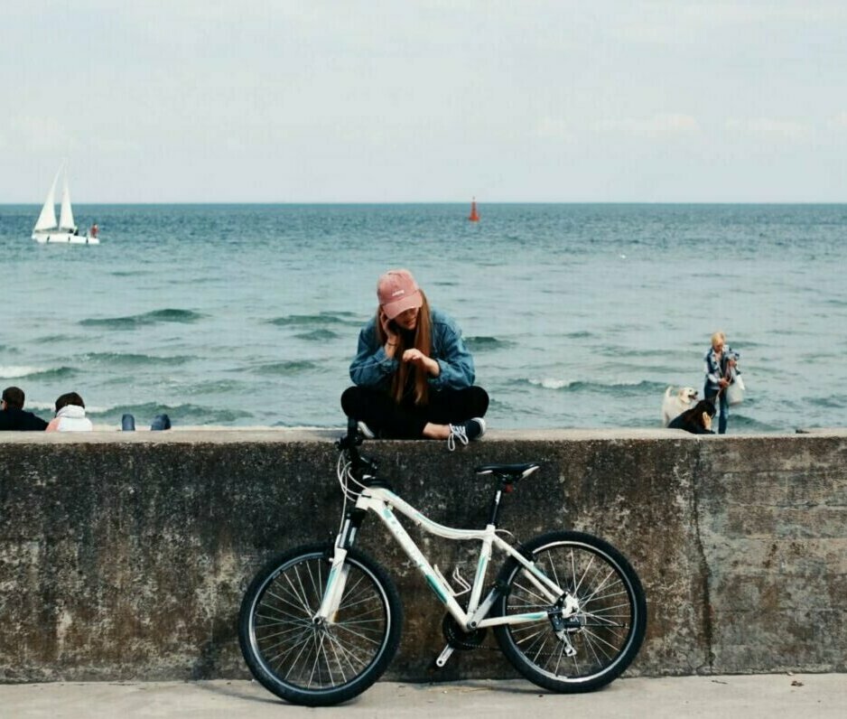 Woman sitting on pier with bicycle. Photo credit: Pawel L.