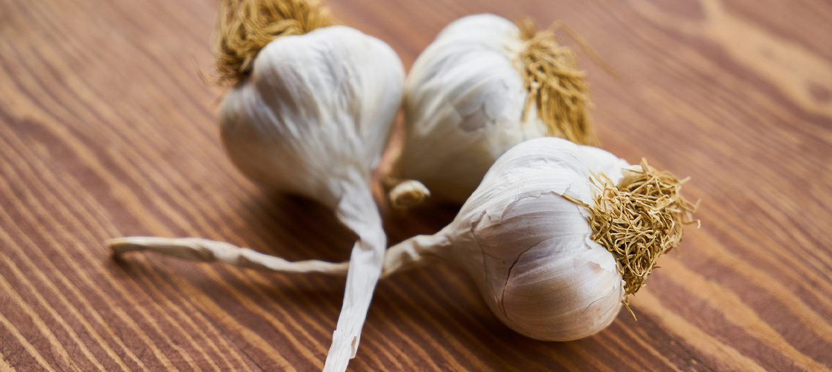 Three heads of garlic on a wooden cutting board