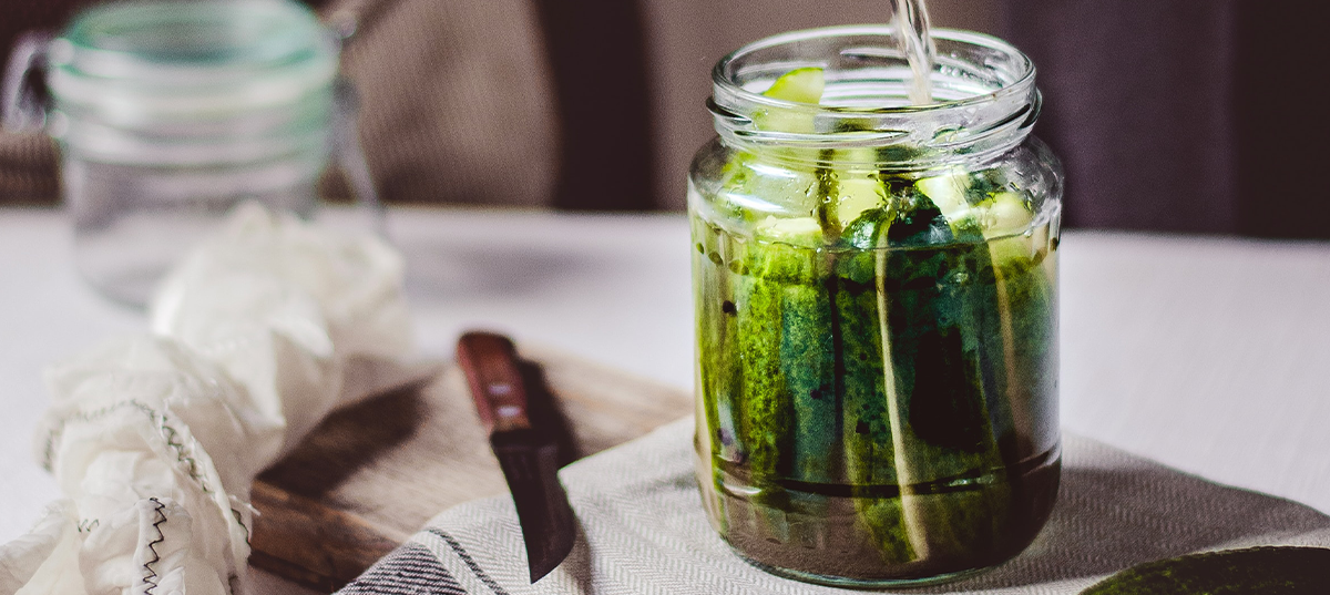 Pouring a water and vinegar mixture into a jar of homemade pickles. Image credit Reka Biro-Horvath