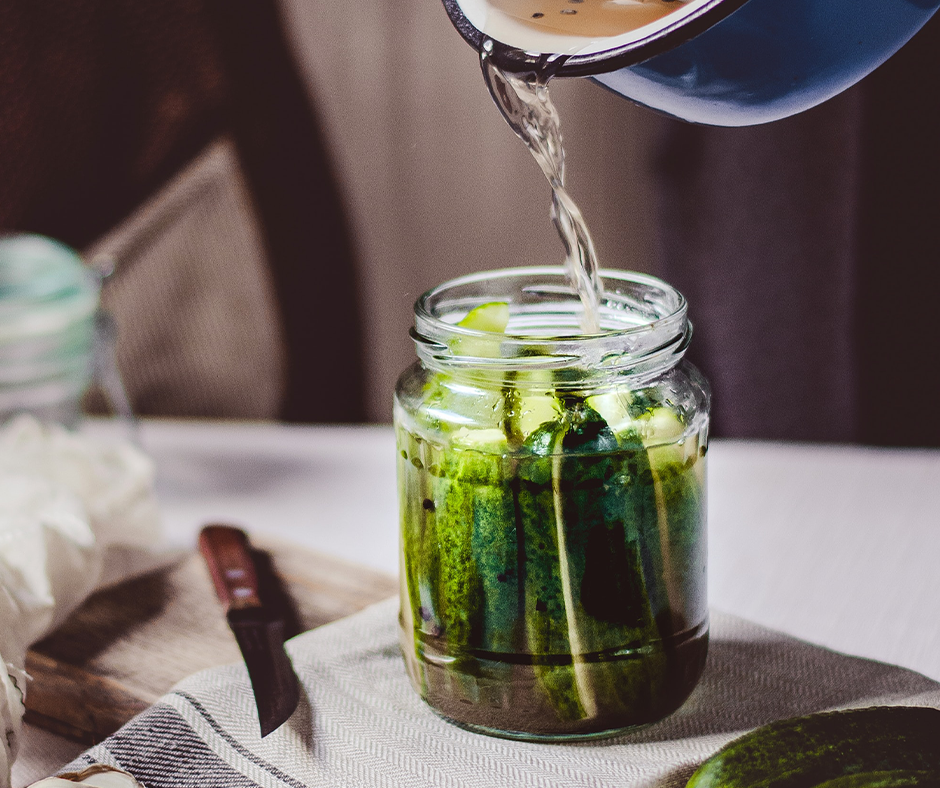 Pouring a water and vinegar mixture into a jar of homemade pickles. Image credit Reka Biro-Horvath