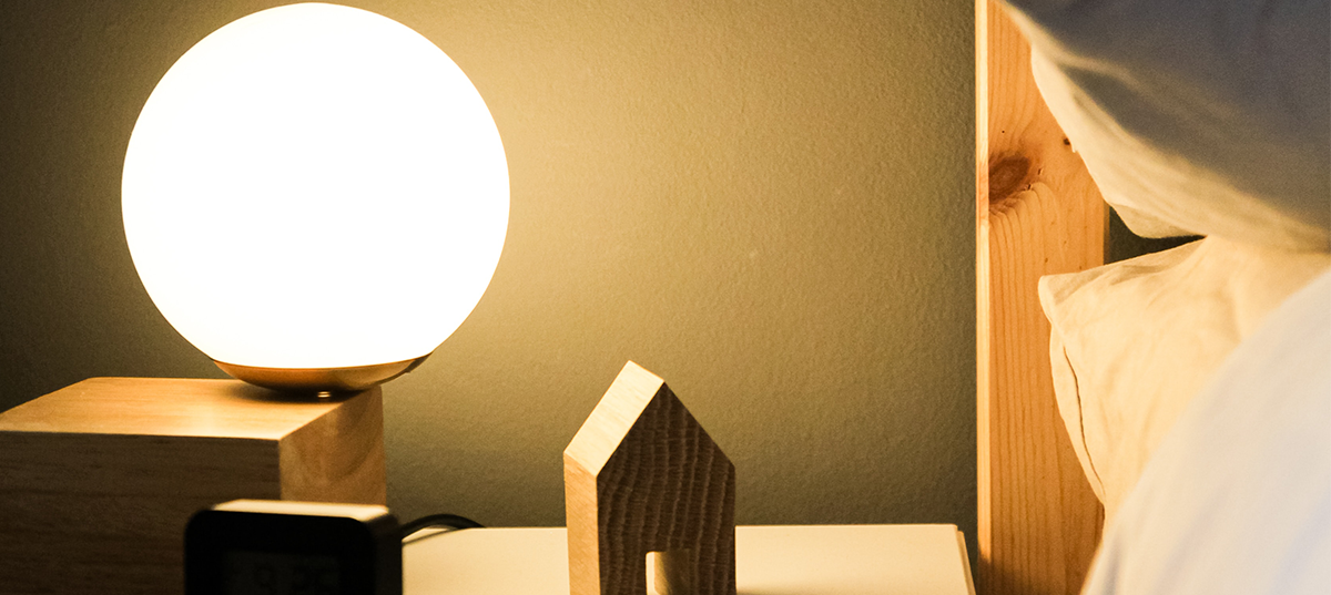 Small glowing lamp on a bedside table. Image credit: Beazy