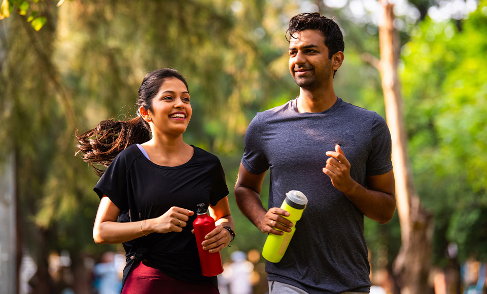 A man and a woman running while holding water bottles