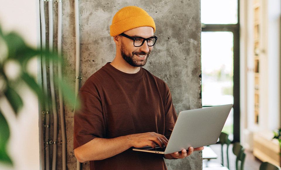 A man in a yellow hat looking at a laptop