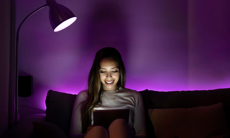 A woman sitting under a purple light reading a book