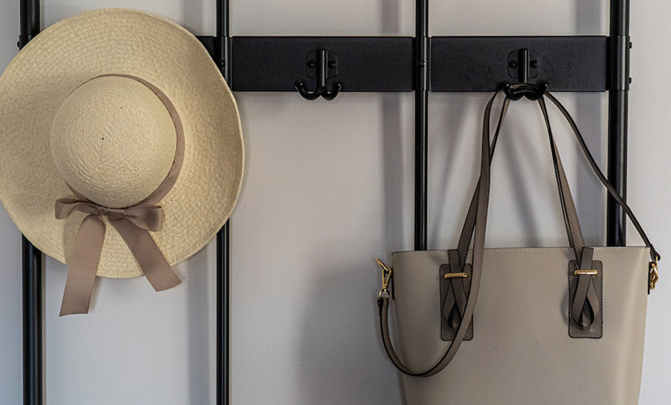 A hat and purse hanging from a coat rack